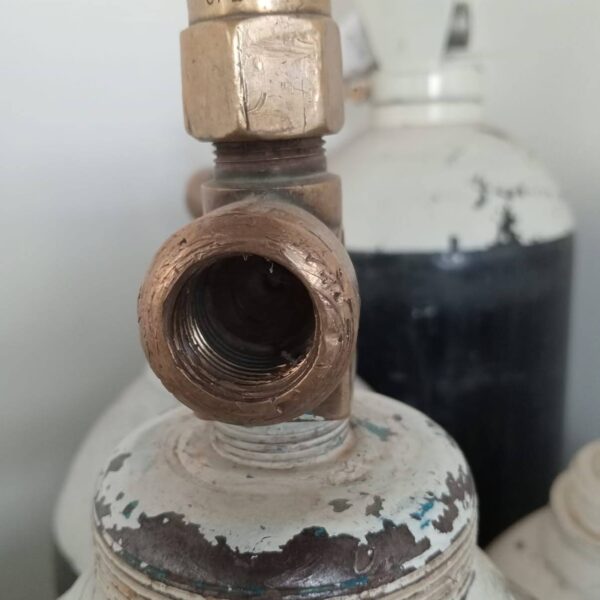Close-up of a corroded and damaged medical oxygen cylinder valve, highlighting the risks of skipping safety recertification.